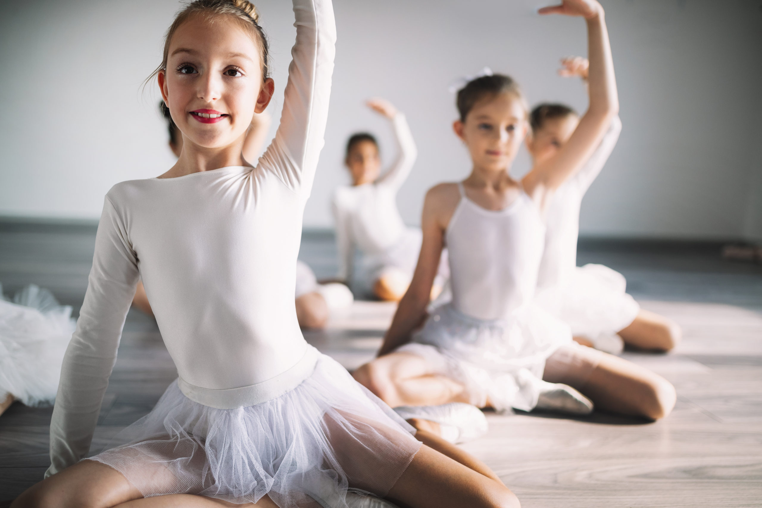 Group of fit happy children exercising ballet in studio together